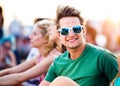 Teenage boy at summer music festival, sitting on ground