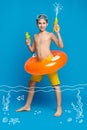 Teenage boy swimming in water with water guns and inflatable ring Royalty Free Stock Photo