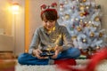 Teenage boy using mobile phone at home in Christmas time Royalty Free Stock Photo