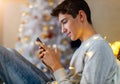 Teenage boy using mobile phone at home in Christmas time Royalty Free Stock Photo