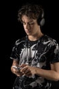 Teenage Boy Using Phone with headset, isolated on black