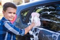 Teenage boy washing a car on a sunny day Royalty Free Stock Photo