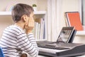 Boy watching video lesson at tablet computer and learing playing digital piano at home. Online learning remote education Royalty Free Stock Photo