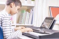 Teenage boy watching video lesson at tablet computer and playing digital piano at home. Online learning remote education Royalty Free Stock Photo