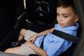 A teenage boy wearing seat belts travels by car in a protective child booster car seat. Traveling safely with children