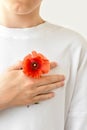 Teenage boy in white t-shirt holding hand with red poppy on chest near heart. Symbol of Remembrance day, Armistice day Royalty Free Stock Photo