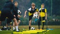 Teenage boys on football training session with two young coaches