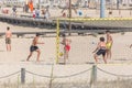 Teenage boys playing beach soccer on the sand at Claridade beach, people going walking on pedestrian walkways as background, Royalty Free Stock Photo