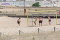 Teenage boys playing beach soccer on the sand at Claridade beach, people going walking on pedestrian walkways as background, Royalty Free Stock Photo