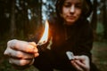 Teenage bully in hood holds burning match in his hand. Forest arsonist. Fire danger. Concept of arson and flame in night Royalty Free Stock Photo