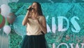 Teenage beautiful girl in dress singing into microfone at show