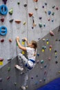 Teenage Caucasian girl climbing wall with holding safety rope, indoor