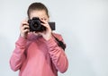 Teenage Caucasian girl taking picture with DSLR camera, front view during shooting, grey background, copyspace Royalty Free Stock Photo