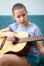 Teenage Caucasian girl tune up acoustic guitar in home