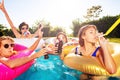 Teenage children blow noisemaker in swimming pool Royalty Free Stock Photo