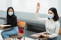 Teenage college students sitting in the class and raising hand up to participate ask question during lecture. High school student Royalty Free Stock Photo