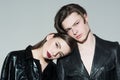 Teenage couple in love wearing black leather jackets isolated on gray background. Stylish brunette girl leaning on her Royalty Free Stock Photo