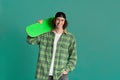 Teenage culture concept. Funky young man with skatebord on color background, space for text