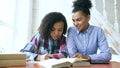 Teenage curly haired mixed race young girl sitting at the table concentrating focused learning lessons and her elder Royalty Free Stock Photo