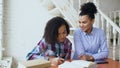 Teenage curly haired mixed race young girl sitting at the table concentrating focused learning lessons and her elder Royalty Free Stock Photo