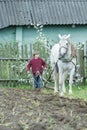 Teenage farm worker and white horse during traditional single-sided ploughing Royalty Free Stock Photo