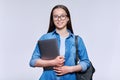 Teenage female student with backpack laptop looking at camera on light background