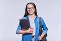 Teenage female student with backpack laptop looking at camera on light background Royalty Free Stock Photo