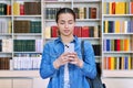 Teenage female student using smartphone, inside high school building, in library Royalty Free Stock Photo