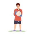 A teenage football player goalkeeper in a red sports shirt caught a soccer ball. Kid athlete plays football, stands at Royalty Free Stock Photo