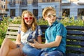 Teenage friends girl and boy sitting on bench in city, talking. Friendship and people concept Royalty Free Stock Photo