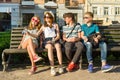 Teenage friends girl and boy sitting on the bench in the city, talking, looking in the phone, doing selfie photo Royalty Free Stock Photo