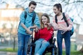 Teenage Friends With Girl In Wheelchair Looking At Mobile Phone As They Leave High School Royalty Free Stock Photo