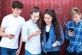 Group Of Teenage Froends Looking At Mobile Phones In Urban Setting Royalty Free Stock Photo