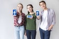 Teenage friends showing smartphones with facebook logo isolated on grey