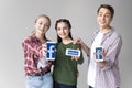 Teenage friends showing smartphones with facebook logo isolated on grey