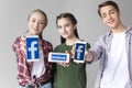 Teenage friends showing smartphones with facebook logo isolated on grey