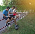 Teenage friends using a smartphone sitting on an outdoor playground fence - Young Mobile Smartphone Addicts Royalty Free Stock Photo