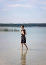 A teenage girl alone walks barefoot on the water of a lake with a book in her hands. Meditation Royalty Free Stock Photo