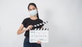 Teenage Girl or asian young woman wear face mask and hand`s holding clapper board or movie slate use in video production ,film, Royalty Free Stock Photo