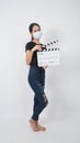 Teenage Girl or asian young woman wear face mask and hand`s holding clapper board or movie slate use in video production ,film, Royalty Free Stock Photo