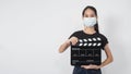 Teenage Girl or asian young woman wear face mask and hand`s holding clapper board or movie slate use in video production ,film, Royalty Free Stock Photo