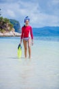 Teenage girl in bikini carrying scubadiving equipment