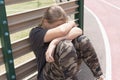 a teenage girl with blond hair sits by a fence near a football field Royalty Free Stock Photo