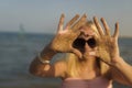 Teenage girl blonde with glasses to keep her hands in the sand by the sea Royalty Free Stock Photo