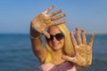 teenage girl blonde with glasses to keep her hands in the sand by the sea Royalty Free Stock Photo