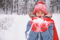 a teenage girl is blowing on the snow in her palms and fanning, mittens and a knitted hat, changing weather Royalty Free Stock Photo