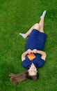 A teenage girl is lying outside on the lawn, smiling and playing with popit and simple dimple antistress toys.