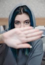 A teenage girl with blue hair covers her face with her hand Royalty Free Stock Photo