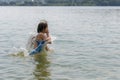 Teenage girl in blue swimsuit bathes in calm cool lake water in hot summer, raising a lot of splashes Royalty Free Stock Photo