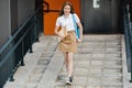 A teenage girl with a book and a backpack goes down the stairs and goes to school. Education, training, back to school